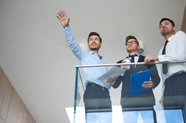 Tres directivos observando el horizonte desde el balcón de una oficina